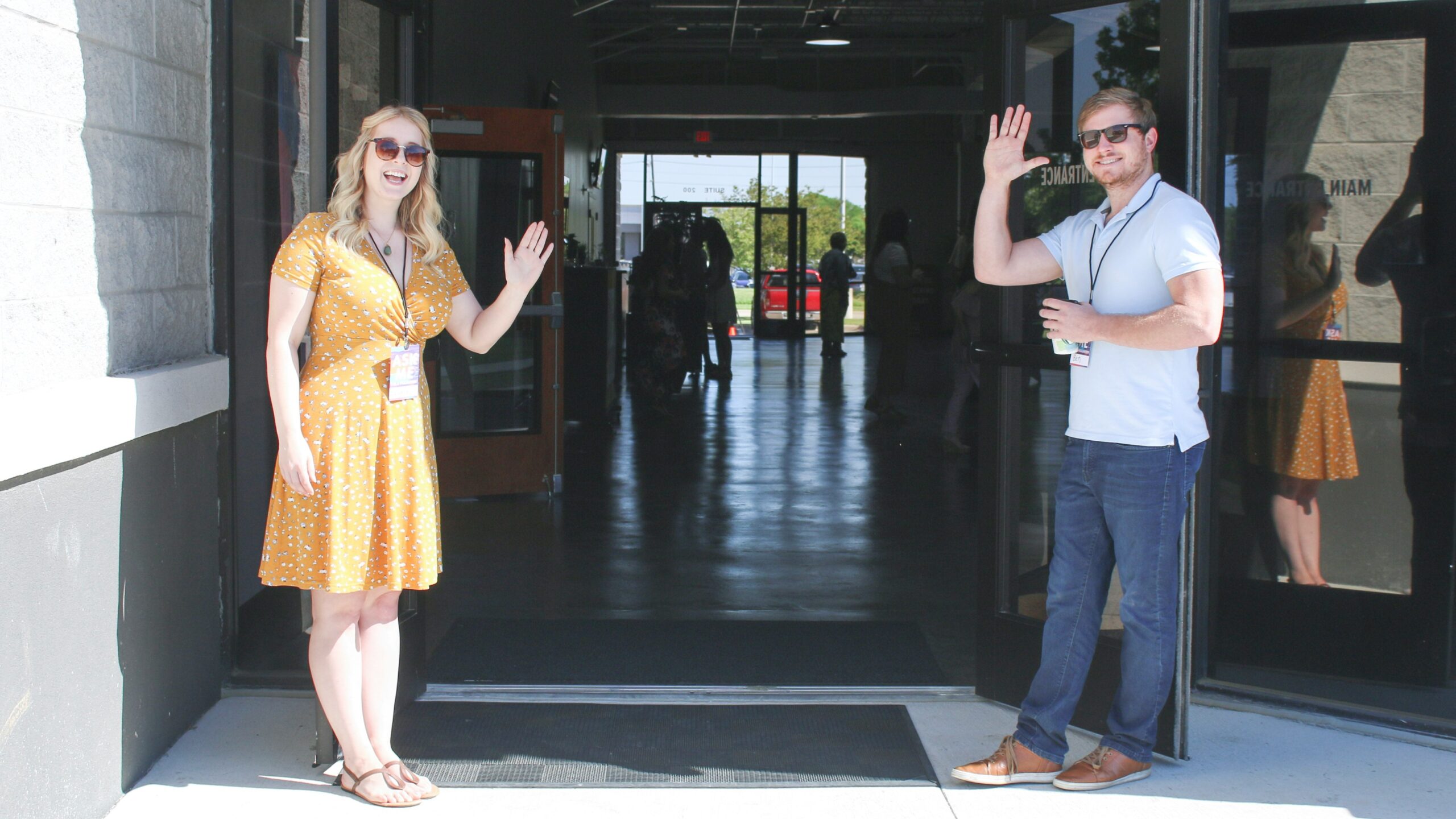 man and woman standing at entrance of church, waving hello