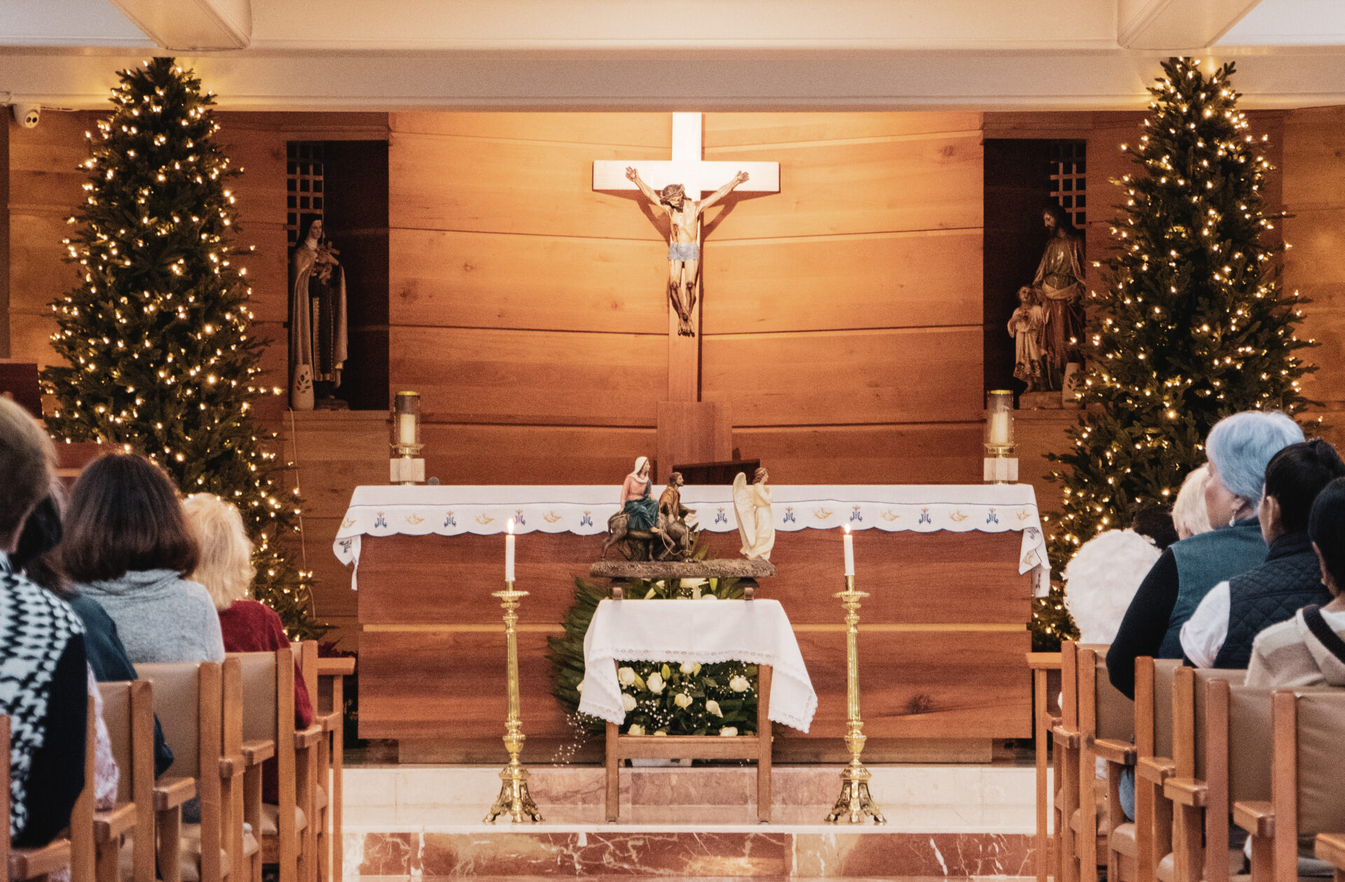 a christmas scene in a parish - parishioners looking at a crucifix with christmas trees on either side