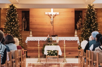 a christmas scene in a parish - parishioners looking at a crucifix with christmas trees on either side